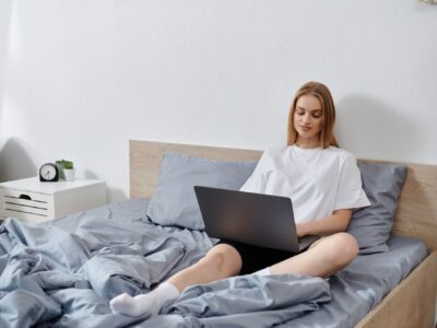 Young Woman Relaxing on Bed With Laptop